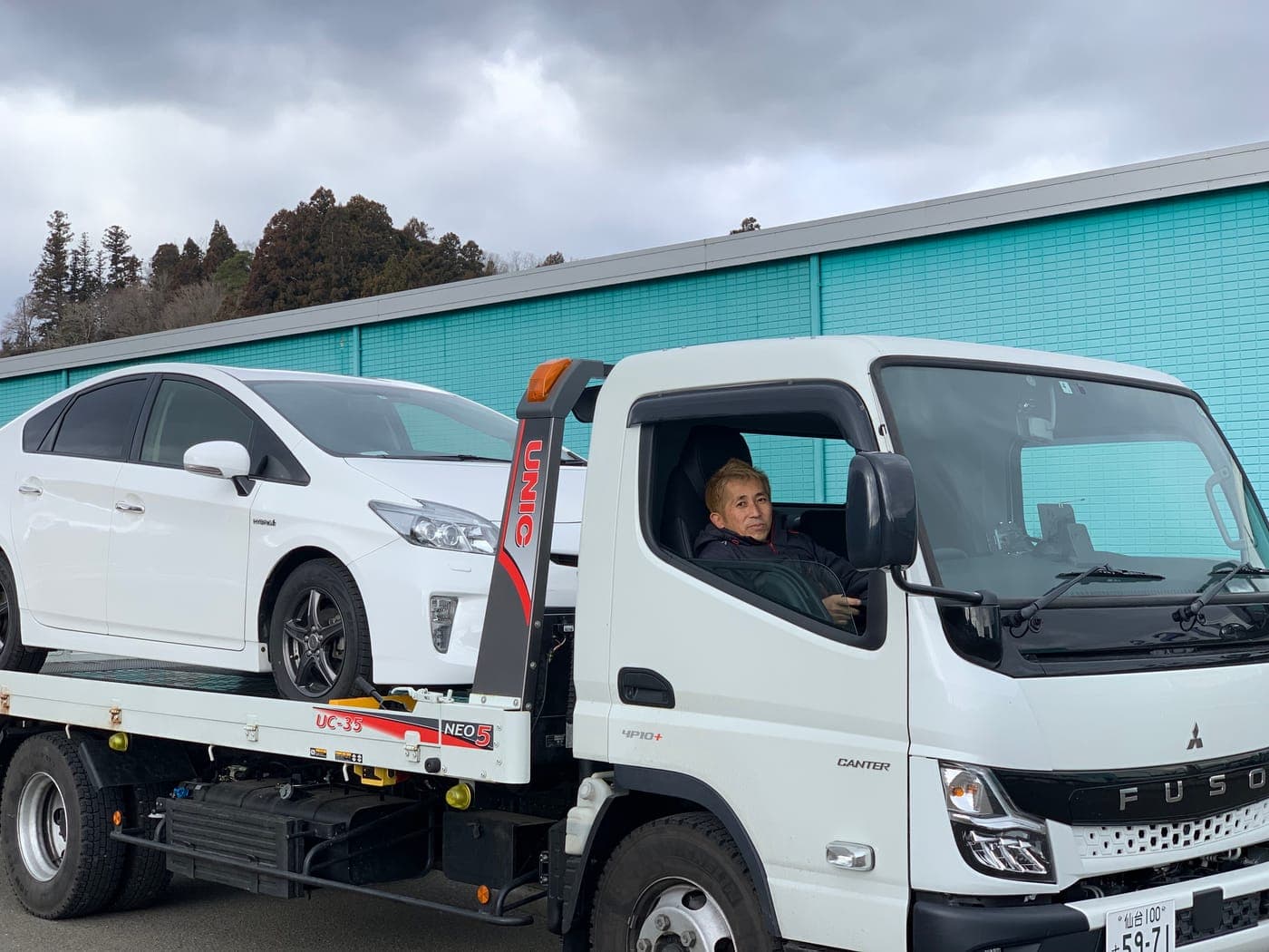 Ito Tadadaka driving a transport truck carrying a white Toyota Prius