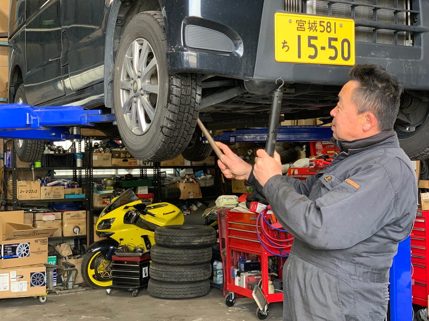 Takashi Iwabuchi checking the underside of a car on a lift